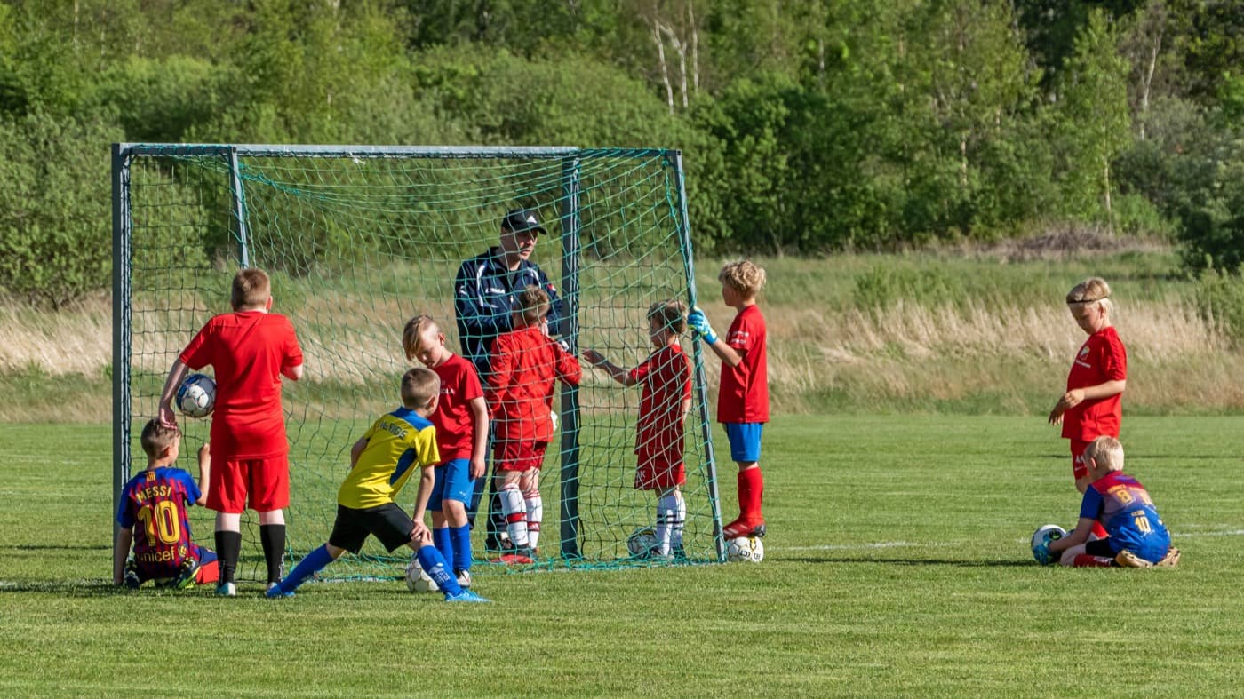 Children practicing soccer together around a goal